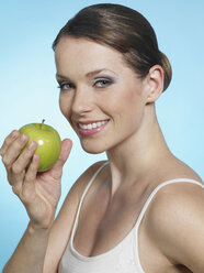 Young woman holding green apple, smiling, portrait - JLF000304