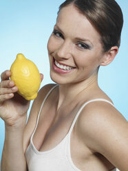 Junge Frau mit Zitrone in der Hand, lächelnd, Porträt - JLF000305