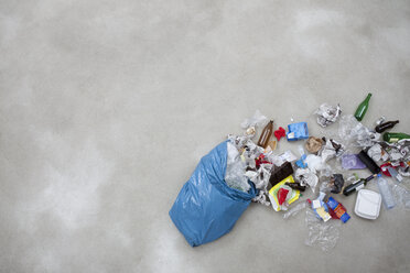 Müll, der aus einer Plastiktüte austritt, auf grauem Hintergrund - BAEF000179