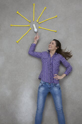 Mid adult woman pointing at electric bulb, smiling - BAEF000214