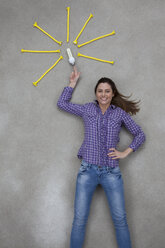Mid adult woman pointing at electric bulb, smiling, portrait - BAEF000215