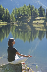 Austria, Styria, Mid adult woman meditating at lake duisitzkar in schladming - HHF003538