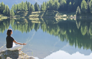 Österreich, Steiermark, Mittlere erwachsene Frau beim Meditieren am Duisitzkarsee in Schladming - HHF003539