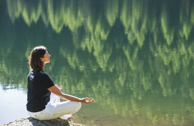 Austria, Styria, Mid adult woman meditating at lake duisitzkar in schladming - HHF003542