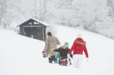 Österreich, Salzburg, Hüttau, Familie mit Laterne geht durch Schnee - HHF003605