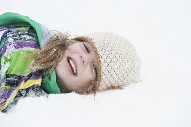 Österreich, Salzburg, Hüttau, Mädchen im Schnee liegend, lächelnd, Porträt - HHF003608
