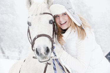 Österreich, Salzburg, Hüttau, Junge Frau mit weißem Pferd, lächelnd - HHF003618