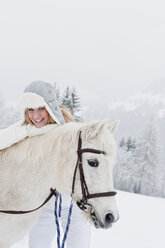 Österreich, Salzburg, Hüttau, Junge Frau mit weißem Pferd, lächelnd, Porträt - HHF003619