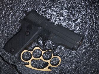 Brass knuckles and pistol on asphalt - AKF000334