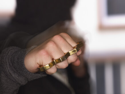 Young man showing fist with brass knuckles - AKF000333