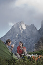 Österreich, Salzburg, Filzmoos, Pärchen sitzt neben Zelt auf Berg - HHF003545