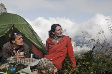 Österreich, Salzburg, Filzmoos, Pärchen sitzt neben dem Zelt auf dem Berg und betrachtet die Aussicht - HHF003546