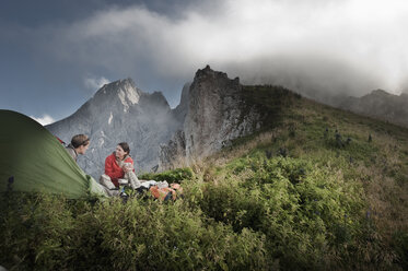 Austria, Salzburg Country, Filzmoos, Couple sitting beside tent on mountains - HHF003561