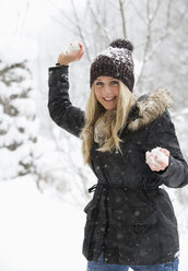 Austria, Teenage girl with snowball, smiling, portrait - WWF001894