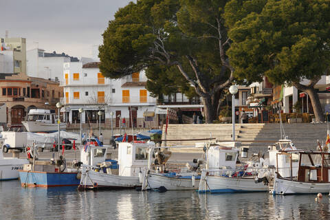 Spanien, Balearische Inseln, Mallorca, Cala Ratjada, Blick auf ein vertäutes Boot mit Gebäuden im Hintergrund, lizenzfreies Stockfoto