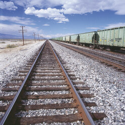 USA, Leeres Eisenbahngleis und vorbeifahrender Güterzug - WBF000985