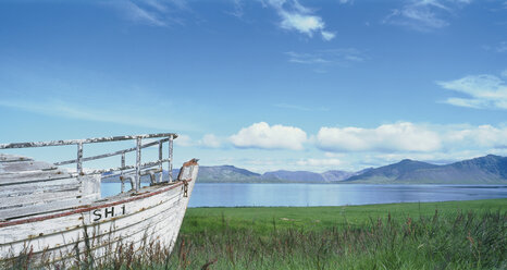 Iceland, Snaefelnes, View of old boat at fjord shore with mountains - WBF000853