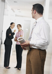 Young businesswoman whispering and businessman listnening - WBF001214