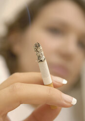 Nahaufnahme des Fingers einer Frau, der eine verbrannte Zigarette hält - WBF001216