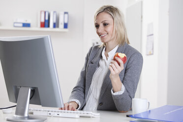 Deutschland, Bayern, München, Geschäftsfrau mit Computer und Apfel in der Hand - RBF000498