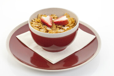 Cornflakes mit Erdbeere in roter Schale auf Teller - MAEF003236