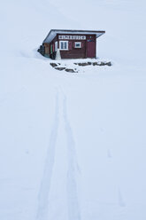 Austria, Vorarlberg, Wood hut with snow trail on mountain - WDF000862