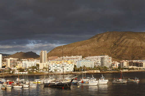 Spanien, Kanarische Inseln, Teneriffa, Los Cristianos, Blick auf Boote im Wasser mit Gebäuden und Bergen im Hintergrund - SIEF001045