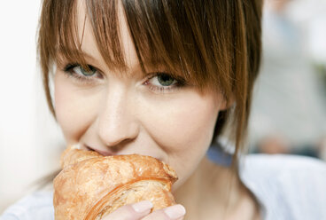 Germany, Cologne, Woman eating croissant - FMKF000191