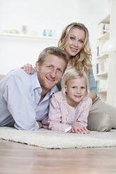 Deutschland, Bayern, München, Eltern mit Tochter auf Teppich liegend, lächelnd, Porträt - RBF000552
