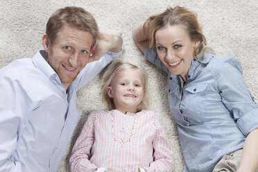 Germany, Bavaria, Munich, Parents with daughter lying on carpet, smiling, portrait - RBF000562