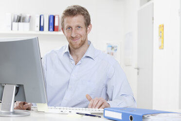 Germany, Bavaria, Munich, Businessman using computer, smiling, portrait - RBF000568