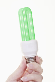 Hand of woman holding green lightbulb against white background, close up - TSF000215