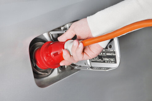 Hand of woman holding high voltage cable loading up electric car, close up - TSF000222