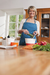 Germany, Kratzeburg, Senior woman cutting vegetables, smiling - WESTF016594