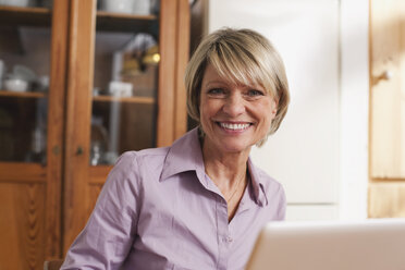 Germany, Kratzeburg, Senior woman with laptop, smiling, portrait - WESTF016598