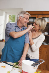 Germany, Kratzeburg, Senior man feeding cucumber slice to senior woman - WESTF016665