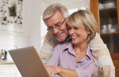 Germany, Kratzeburg, Senior couple using laptop, smiling - WESTF016680
