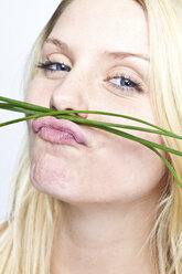 Young woman smelling chives, portrait - MBEF000079