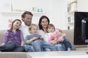 Deutschland, Bayern, München, Familie sitzt auf dem Sofa und sieht fern, lächelnd - RBF000600