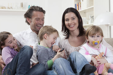 Germany, Bavaria, Munich, Family sitting together on couch, laughing - RBF000601