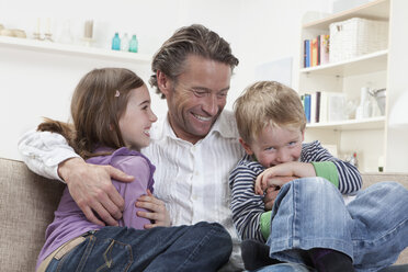 Germany, Bavaria, Munich, Father with kids on couch, laughing - RBF000602