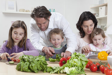 Deutschland, Bayern, München, Mutter und Vater helfen Kindern bei der Zubereitung von Salat - RBF000605