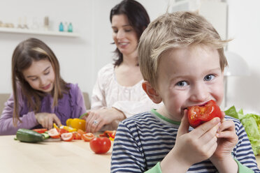 Deutschland, Bayern, München, Mutter und Tochter bereiten Salat zu, Sohn isst - RBF000613