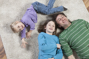 Germany, Bavaria, Munich, Father lying on carpet with son and daughter - RBF000668
