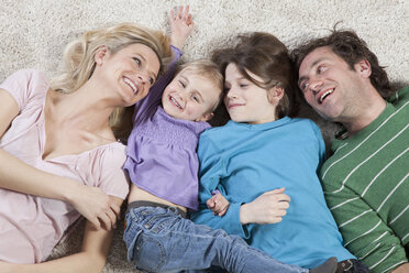 Germany, Bavaria, Munich, Family lying on carpet, smiling - RBF000617