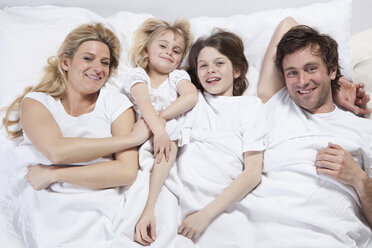 Germany, Bavaria, Munich, Family lying in bed, smiling, portrait - RBF000621