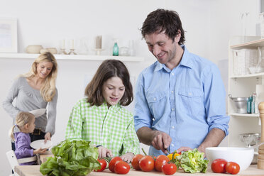 Germany, Bavaria, Munich, Son preparing salad with father, mother and daughter in background - RBF000624