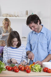 Germany, Bavaria, Munich, Son preparing salad with father, mother and daughter in background - RBF000625