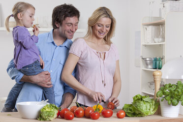Germany, Bavaria, Munich, Mother preparing salad with father and daughter standing beside her - RBF000633
