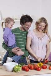 Germany, Bavaria, Munich, Mother preparing salad with father and daughter standing beside her - RBF000635